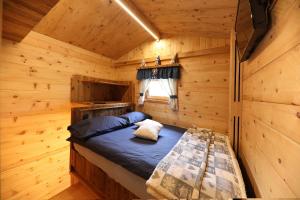 a bed in a log cabin with a window at Chalet El Baitel in Bellamonte