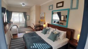 Un dormitorio con una cama grande y un espejo. en View from the Hill room 1, en Mossel Bay