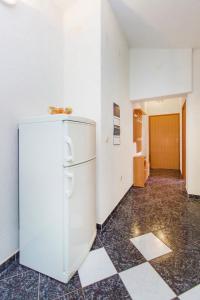 Un refrigerador blanco en una habitación con piso de baldosas. en Apartmani Maestral, en Grebaštica