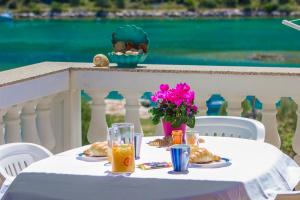 una mesa blanca con comida y flores en el balcón en Apartmani Maestral, en Grebaštica