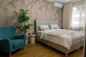 ein Schlafzimmer mit einem Bett und einem blauen Stuhl in der Unterkunft Golden Light - 3BR Luxury Central in Bŭnzareto