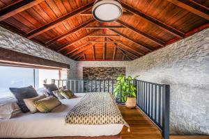 a bedroom with a large bed with a wooden ceiling at NEW! Nature Paradise with Ocean View & Hot Tubs in Fajã da Ovelha +95 photos