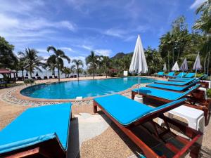 a row of blue lounge chairs next to a swimming pool at Diamond Beach Resort in Ao Nam Mao