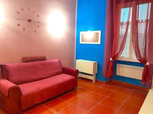 a living room with a red couch and a clock on the wall at LA CASA DI CARTA red in Fiuggi