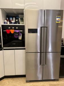 einen Kühlschrank aus Edelstahl in einer Küche mit weißen Schränken in der Unterkunft Madinaty Stunning Villa in Madinaty