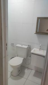 a white bathroom with a toilet and a sink at Apartamento Centro de Tauá in Tauá