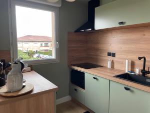 a kitchen with a counter and a sink and a window at Aux Cyprès du littoral T 2 avec piscine in Poussan +8 photos