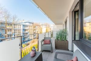 einen Balkon mit Stühlen, einem Tisch und einem Fenster in der Unterkunft APT Nadmorskie - Bliżej Morza in Kołobrzeg