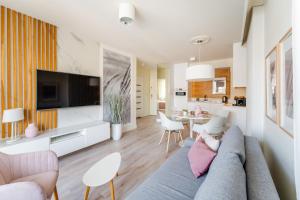 ein Wohnzimmer mit Sofa und Fernseher in der Unterkunft APT Nadmorskie - Bliżej Morza in Kołobrzeg
