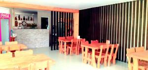 a restaurant with red tables and chairs and a fireplace at Villa Ureki in Ureki