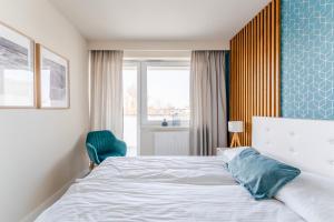 ein Schlafzimmer mit einem Bett, einem Stuhl und einem Fenster in der Unterkunft APT Nadmorskie - Bliżej Morza in Kołobrzeg