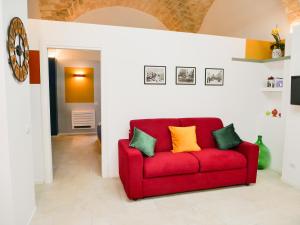 un divano rosso in un soggiorno con cuscini verdi e gialli di SaraHome a Bari