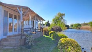 a house with a porch next to a river at Waterlodge met waterfiets op monumentaal fort in Ooltgensplaat