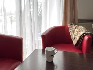 a coffee cup sitting on a table next to a chair at Apartament Krola Stefana Batorego in Kielce