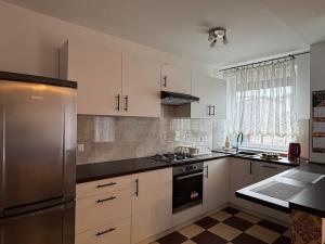 a kitchen with white cabinets and a stainless steel refrigerator at Apartament Krola Stefana Batorego in Kielce