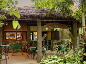 a restaurant with tables and chairs and a thatch roof at Hotel Saint jean Leopold Apartment in Kigali