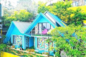 a blue house with a pink chair on a balcony at Mimosa 7- phòng săn mây in Tam Ðảo