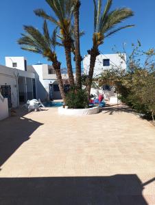 un patio con due palme e un edificio di Villa avec piscine Dar Khadouja à Djerba a Beni Dinhet