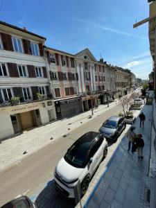 two cars parked on a city street with buildings at Appartement centre ville in Albertville