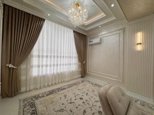 a living room with a chandelier and a chair at Samarkand Premium Apartment 2 in Samarkand