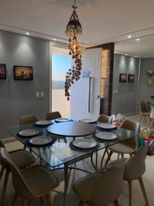 a dining room with a table with chairs and a chandelier at Apartamento em Praia de Cotovelo in Parnamirim
