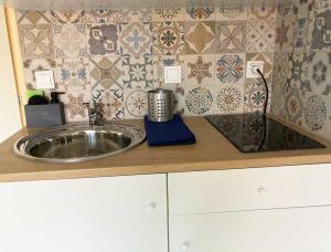 a kitchen counter with a sink and a tile wall at BananaHouse in Kefallonia