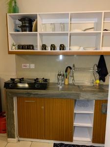 a kitchen with a counter top with shelves at Lux Suites Coral Bells Studio Apartments in Kiambu