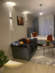 a living room with a couch and a bed at Lux Suites Coral Bells Studio Apartments in Kiambu