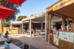 a restaurant with tables and chairs and an umbrella at Neptune 158 Argeles in Argelès-sur-Mer