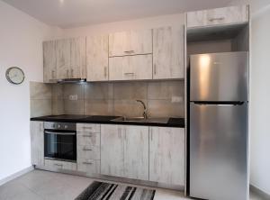 a kitchen with wooden cabinets and a stainless steel refrigerator at Melodia Lefkada Apartment 2 in Nikiana
