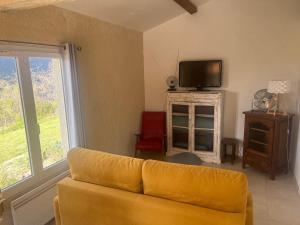 a living room with a yellow couch and a tv at Cabanon entouré de montagnes et d'oliviers in Nyons