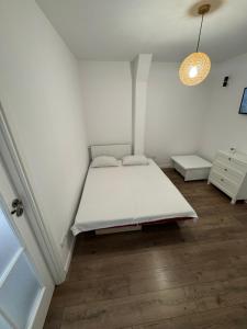 a white bedroom with a bed and a lamp at Studio Luca in Eforie Nord