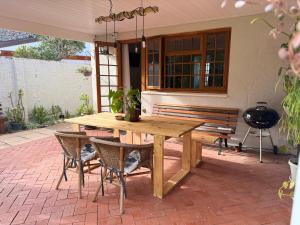 una mesa de madera y sillas en un patio con un banco en Garden Home in Upper Walmer, en Gqeberha