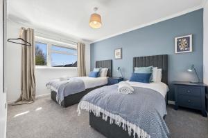 a bedroom with two beds and a window at Cotswolds Vista, 3 bed, 2 bathrooms, complimentary parking in Cirencester