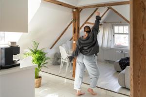 CHILLSET Apartmenty Westerplatte by Lion Apartments في سوبوت: امرأة تقف أمام المرآة في غرفة المعيشة