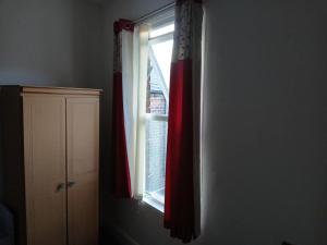a window with a red curtain in a room at Room in town centre in Saint Helens