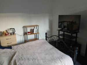 a bedroom with a bed and a dresser and a table at Room in town centre in Saint Helens