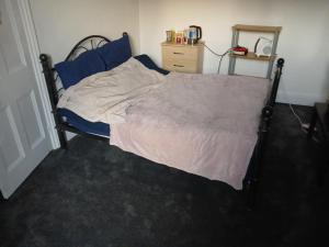 a bedroom with a large bed with blue sheets at Room in town centre in Saint Helens