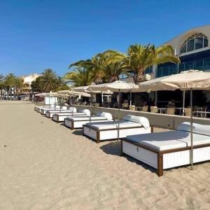 a row of lounge chairs and umbrellas on a beach at La Perla del Pinatar in San Pedro del Pinatar +18 photos