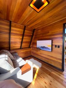 a living room with a couch and a flat screen tv at Vila Chamonix - Chalé Malbec in Urubici
