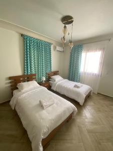 2 łóżka w pokoju z niebieskimi zasłonami w obiekcie Luxury Villa 5 Bedroom Beach House in Sidi Heneish - Mediterranean Sea w mieście Marsa Matruh