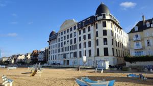 un gran edificio blanco con una playa frente a él en Ton petit coin de paradis avec balcon au Trouville Palace, en Trouville-sur-Mer