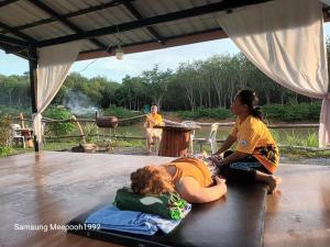 Ko Khang TakPhaluayCamping的两个女人坐在地板上,一个人躺在袋子里