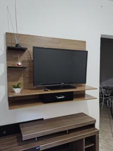 a flat screen tv on a wooden entertainment center at Casinha central Manhuaçu in Manhuaçu