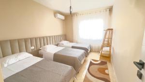 three beds in a room with a window and a ladder at ARZO Apartments in Berat