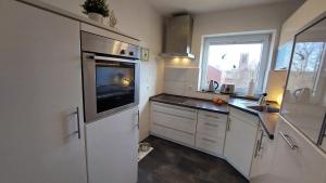 een keuken met witte kasten, een gootsteen en een raam bij Fewo Flutbarke in Wilhelmshaven