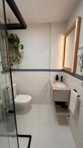 a white bathroom with a toilet and a sink at Seu Refúgio Apartamento moderno e aconchegante no Centro de Juiz de Fora in Juiz de Fora