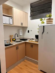 a kitchen with brown cabinets and a white refrigerator at Seu Refúgio Apartamento moderno e aconchegante no Centro de Juiz de Fora in Juiz de Fora