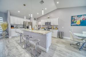 una cucina con armadi bianchi e un'isola con sgabelli da bar di Campos Family Resort - Heated Pool a Cape Coral