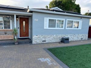 a gray house with a door and a lawn at Hayward Home in Hayward